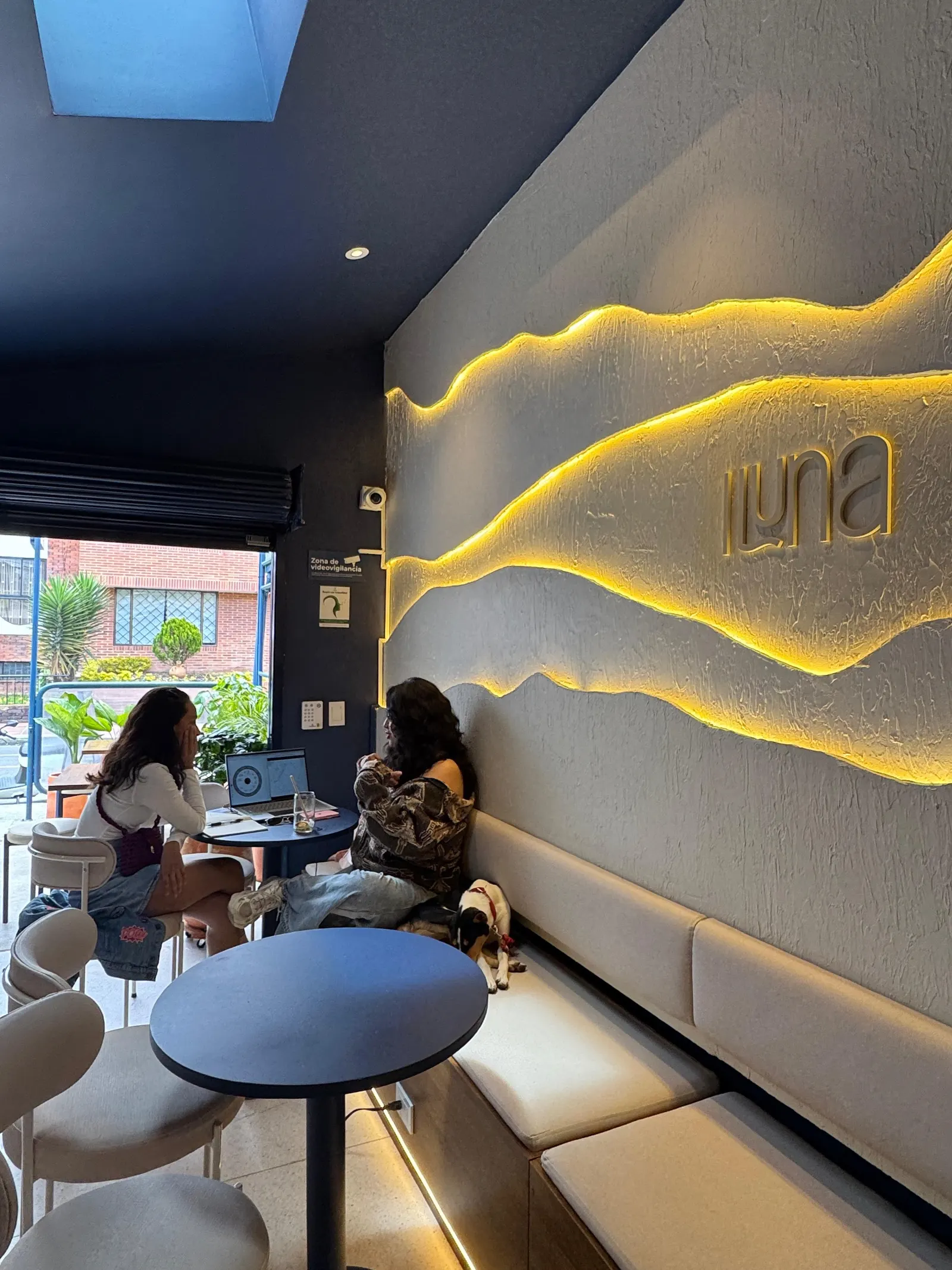 Interior de Iluna con la pared iluminada inspirada en una montaña, mesas y visitantes